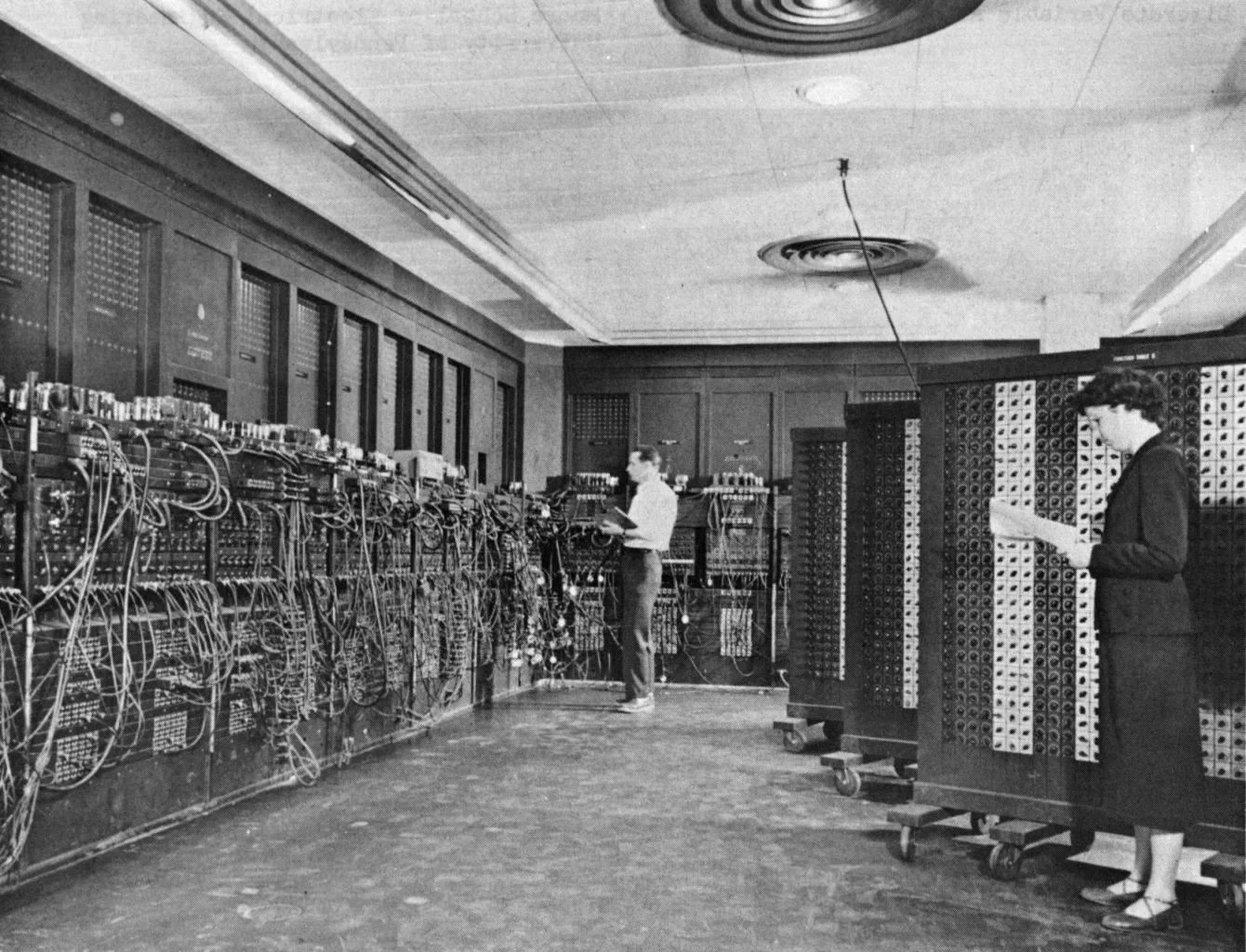 Two programmers at the ENIAC, a room-sized computer of panels, cables and switches.